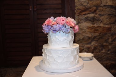 Tatlı çok düzeyli düğün pastası çiçeklerle süslenmiş