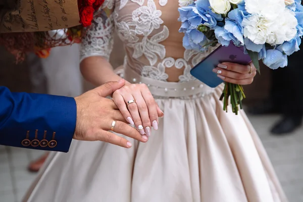 Руки жениха и невесты с обручальными кольцами на цветах — стоковое фото