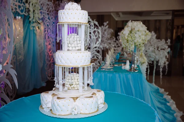 Süße mehrstöckige Hochzeitstorte mit Blumen auf blauem Tisch — Stockfoto