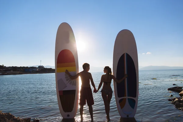 Siluetas de hermosa pareja con sup serf y remo en el océano — Foto de Stock