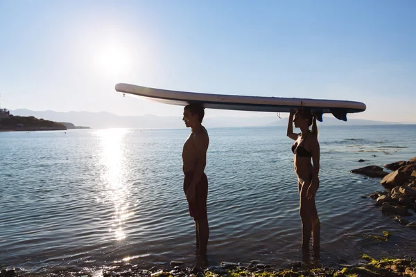 Silueta de pareja perfecta participar stand-up paddle boarding — Foto de Stock