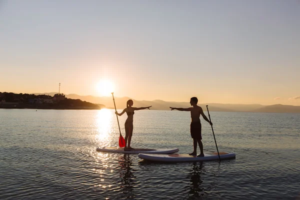 Silueta de pareja perfecta participar stand-up paddle boarding — Foto de Stock