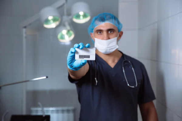 Mannelijke arts tonen visitekaartje en camera kijken — Stockfoto