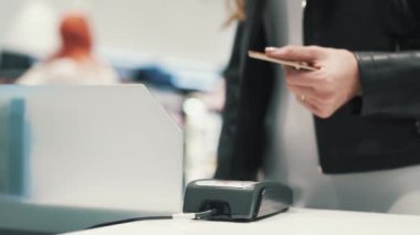 Kimliği belirsiz genç bir kız süpermarkette banka kartıyla ödeme yapıyor.