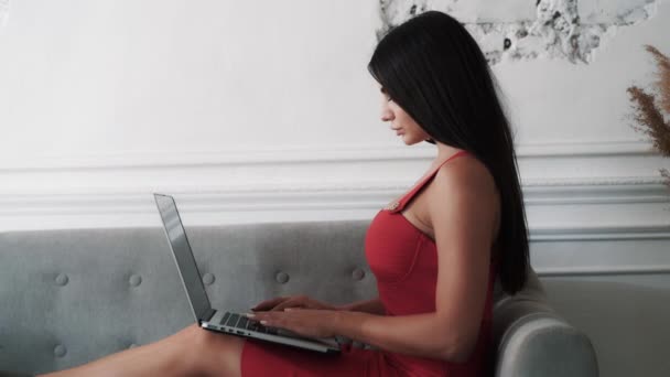 Brunette nainen punaisessa mekossa kirjoittamalla viestin sosiaalisissa verkostoissa — kuvapankkivideo