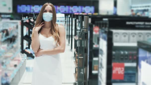 Elbűvölő fiatal kaukázusi lány pózol egy szupermarketben orvosi maszkban — Stock videók