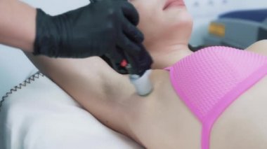 Ustanın elleri koltuk altında lazer epilasyonu yapıyor.