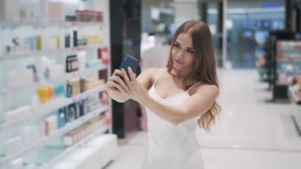 Encantadora jovem mulher caucasiana em um vestido branco faz selfie usando smartphone — Vídeo de Stock