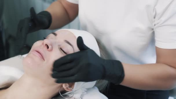 Close up vrouwen gezicht, schoonheidsspecialiste in handschoenen maakt anti-aging gezichtsmassage — Stockvideo