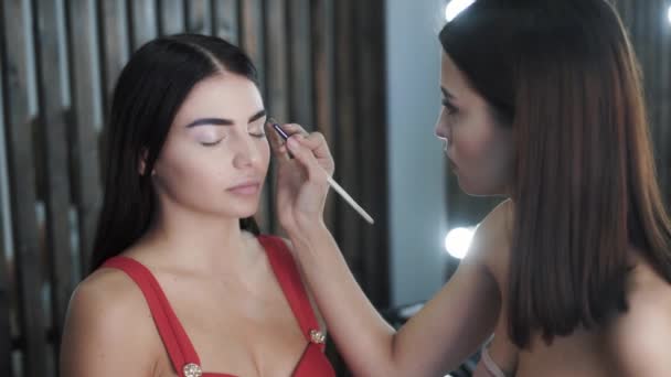 Žena make-up umělec aplikuje make-up na roztomilé mladé kavkazské modelu — Stock video