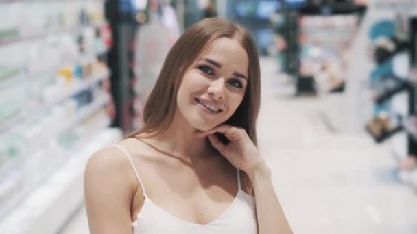 Linda chica joven en vestido blanco posando mientras compra en el supermercado — Vídeos de Stock