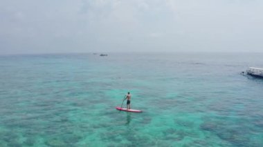 Genç adam Hint Okyanusu 'nun berrak mavi sularında kızıl dalgalarda yüzüyor.