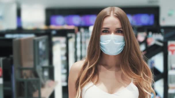 Προσωπογραφία χαριτωμένης καυκάσιας νεαρής γυναίκας με ιατρική μάσκα που ποζάρει στο σούπερ μάρκετ — Αρχείο Βίντεο