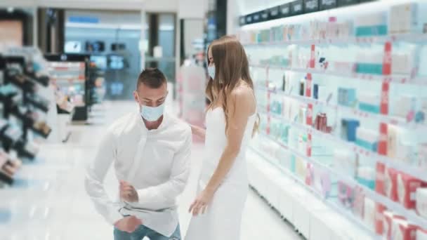 Jong paar meisje en man in medische maskers dansen gek in supermarkt — Stockvideo