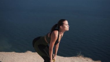 Spor kıyafetleri içinde yavaş çekim çekici genç bir kadın egzersiz yapıyor.