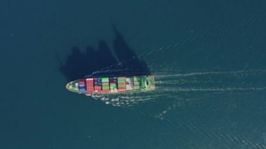 Mavi dalgalarda yüzen bir kargo gemisinin hava görüntüsü.