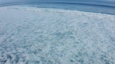 Yavaş çekim deniz köpüğünün hava görüntüsü büyüleyici bir şekilde dalgaları sarıyor. 