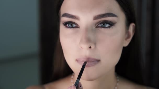 Mujer con maquillaje brillante aplica lápiz labial a sus labios regordetes — Vídeos de Stock