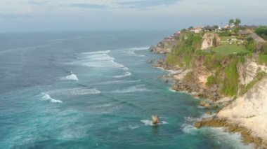 Güzel okyanus dalgalarının hava manzarası güzel bir kayaya doğru sıçrıyor.