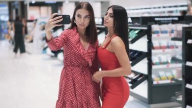 İki çekici genç bayan arkadaş akıllı telefondan selfie çekiyor.