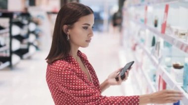 Bakımlı, kırmızı elbiseli güzel esmer kız malların fotoğrafını çekiyor.