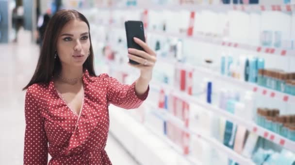 Hermosa joven caucásica morena chica en vestido rojo hace selfie en el teléfono inteligente — Vídeos de Stock