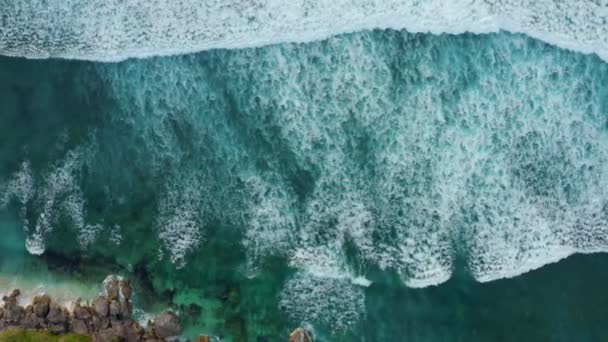 Vista superior é belas ondas do oceano salpicando em direção a uma bela ilha rochosa — Vídeo de Stock