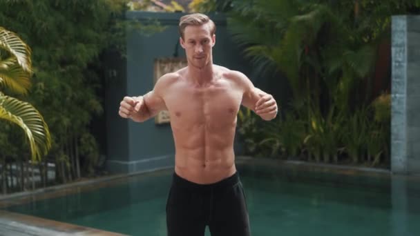 Fitness desportivo caucasiano homem aquece-se ao ar livre à beira da piscina — Vídeo de Stock
