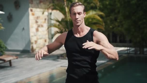 Fitness homem caucasiano desportivo aquecimentos na natureza em frente à piscina — Vídeo de Stock