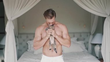 Vahşi ve güçlü beyaz adam küçük sevimli bir kediyle oynuyor.