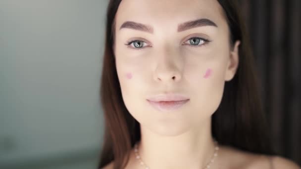 Linda jovem mulher caucasiana encantadora aplicando blush em suas bochechas — Vídeo de Stock
