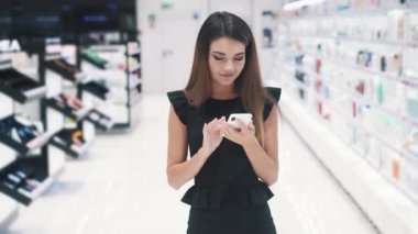 Kafkas 'lı genç bir kadın dükkanda akıllı telefonuyla sohbet ediyor..