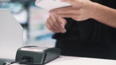 Kadın elinin yan görüntüsü NFC akıllı telefonunu ödemeye getiriyor..