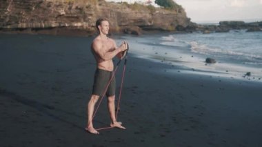 Lastik bantla egzersiz yapan uzun boylu beyaz adamın yan görüntüsü..