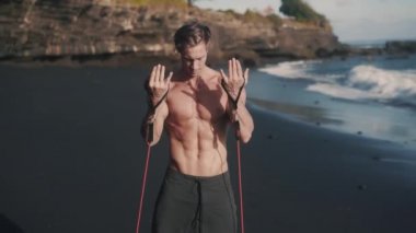 Mükemmel vücut sporcusunun yakın görüntüsü elastik bantla kolları eğitiyor..