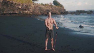 Mükemmel 6 paketli vücut sporcusunun ön görüntüsü elastik bant ile egzersiz yapıyor.