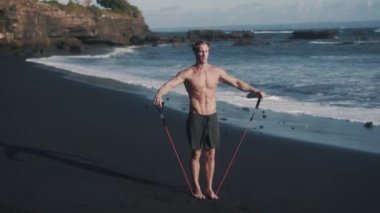 Lastik bantla egzersiz yapan genç sporcunun yan yana videosu.