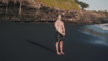 Mükemmel vücut sporcusunun yan görünüşü elastik bantla kolları eğitiyor..