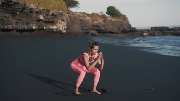Ung attraktiv vit kvinna gör knäböj på stranden på morgonen. — Stockvideo