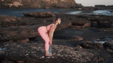 Yan manzara güzel genç bir kadın elastik bantla dışarıda egzersiz yapıyor..