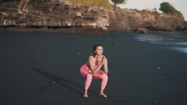 Vue des trois quarts de la jeune femme faisant squats et jambes balançoires latérales. — Video