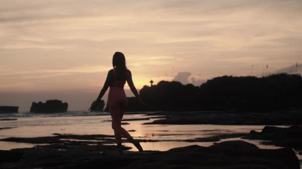 Vista posterior de la joven mujer caucásica haciendo ejercicios de gimnasia en la playa. — Vídeos de Stock
