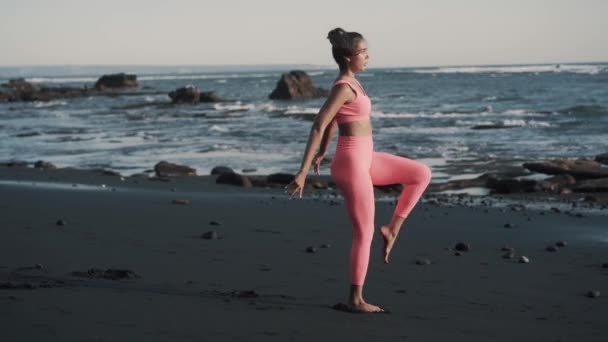 Vue latérale de la jeune femme caucasienne faisant des exercices au bord de la mer. — Video