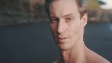 Portrait of young athletic man looking to the camera and stretch out his neck.