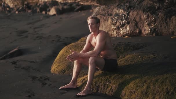 Portrait of young athletic man resting after training on the rock. — Stock video