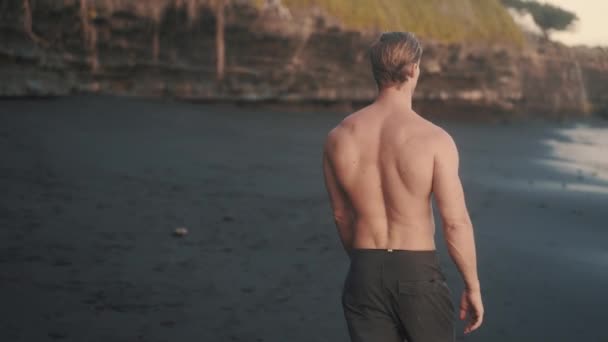 Atletische blanke man met brede rug wandelen topless op de kust. — Stockvideo