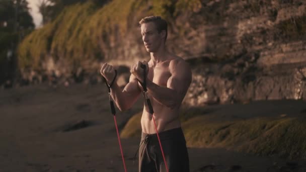 Młody sportowiec trenuje bicepsy i tricepsy na piaszczystej plaży z bliska. — Wideo stockowe