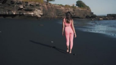 Genç Kafkas fitness modelinin deniz kıyısında yürüyüşünün arka görüntüsü.