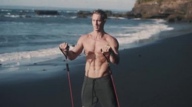 Mükemmel vücut sporcusunun yakın görüntüsü elastik bantla kolları eğitiyor..