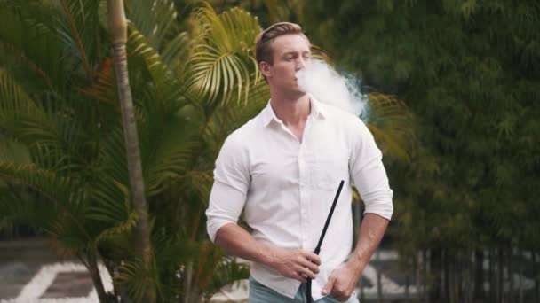 Медленное видео, где белый мужчина курит кальян и расслабляется. — стоковое видео